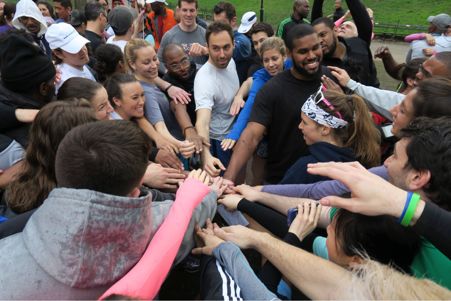 Back on My Feet members and volunteers coming together for a Circle Up, hands in
